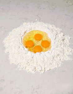 four eggs are in a floured bowl on a white countertop, with the rest of the ingredients visible