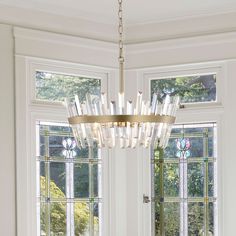 a chandelier hangs from the ceiling in front of two windows with stained glass panes