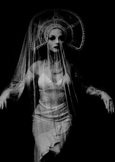 a black and white photo of a woman with veil on her head, in the dark