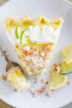 a slice of lemon pie on a white plate with a fork and lime wedges