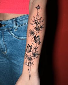 a woman's arm with flowers and butterflies tattoo on the left side of her arm