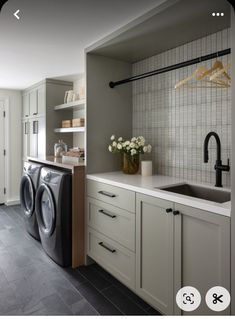 a washer and dryer in a kitchen with white cabinets, gray flooring