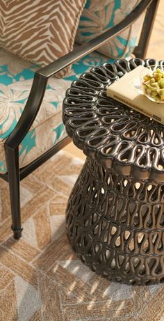 a table with a book on top of it next to a chair and pillows in the background