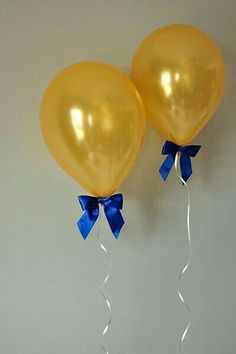 two yellow balloons with blue bows on them