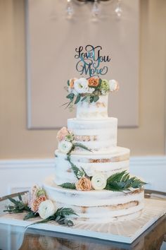 a white wedding cake with flowers and greenery