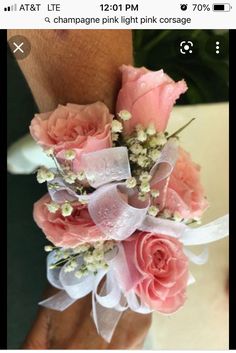 a wrist corsage with pink roses and baby's breath flowers on it