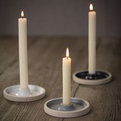 three white candles sitting on top of a table next to each other with one candle in the middle