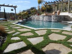 an outdoor pool surrounded by stone steps and grass