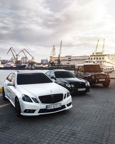 three mercedes benzs parked next to each other in front of a body of water