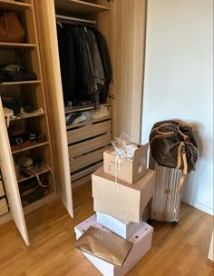 boxes stacked on top of each other in front of a closet with clothes and handbags