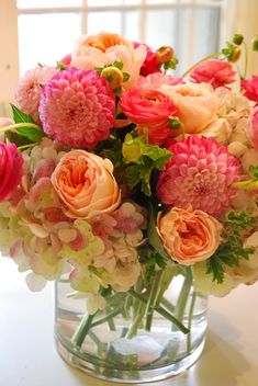 a vase filled with pink and white flowers on top of a table next to a window