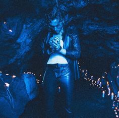 a woman standing in front of a cave with candles