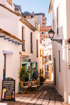 a man sitting at a table in the middle of an alleyway between two buildings