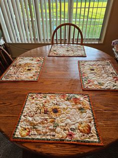 four placemats sitting on top of a wooden table in front of a window