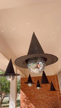 an upside down mirror hanging from the ceiling in front of a brick wall with black cone lights