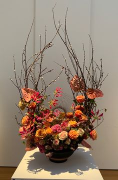 a vase filled with lots of colorful flowers on top of a white table next to a wall