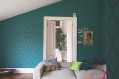 a living room with blue walls and green wallpaper, white couches and colorful pillows