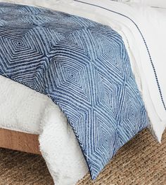 a bed with blue and white bedspread on top of carpeted flooring