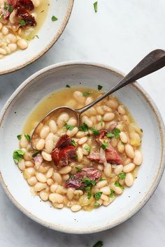 two white bowls filled with beans and ham