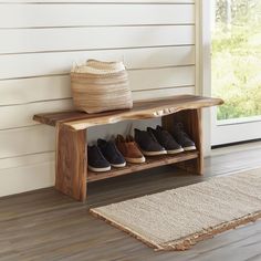 a wooden bench with several pairs of shoes on it and a rug next to it