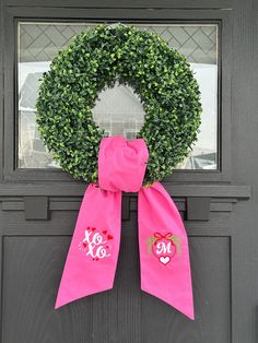 a pink wreath with monogrammed letters on the front door