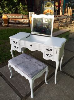 an antique vanity with mirror and stool in front of a house on the side walk