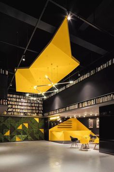 an empty library with yellow bookshelves and stairs in the center, surrounded by black bookcases