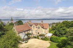 an aerial view of a large house with trees and water in the background