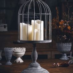 three candles in a birdcage on a table