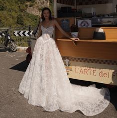 a woman in a wedding dress standing next to a food truck with her hand on the counter