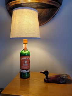 a lamp that is next to a bottle on a table with a duck figurine