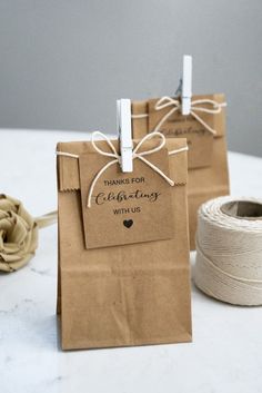 two brown paper bags tied with twine on top of a white table next to a spool of twine