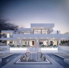 an exterior view of a modern house at night with pool and lounge chairs in the foreground