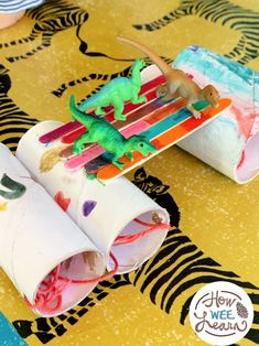 two small toy dinosaurs sitting on top of some wrapping paper roll holders with toothbrushes sticking out of them