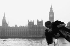 a man and woman kissing in front of the big ben clock tower on a foggy day