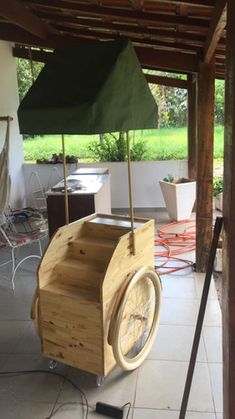 a wheelbarrow is sitting on the floor under an awning with a green umbrella