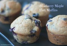 four blueberry maple flax muffins on a black plate with the words blueberry maple flax muffins