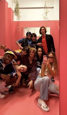 a group of young people taking a selfie in a pink room with red walls