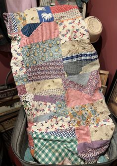 an old quilt sitting on top of a trash can