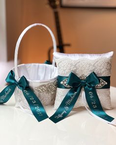 two white baskets with green ribbons and bows on top of a table next to each other