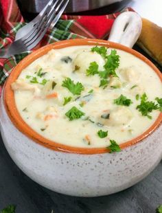 a close up of a bowl of soup on a table with a fork and knife