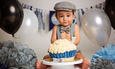 a little boy sitting in front of a cupcake with a bow tie on it