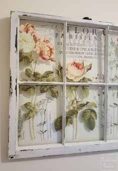 an old window is decorated with flowers and words on the glass paneled wall above it