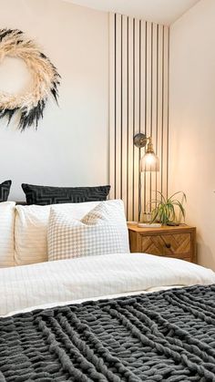 a bed with white sheets and pillows in a bedroom next to a wall mounted clock