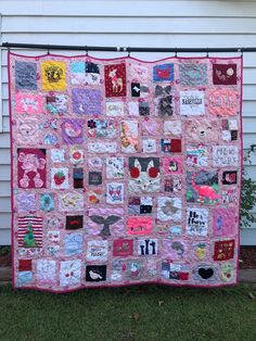 a pink quilt is hanging on the side of a white house and it has many different designs