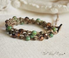 a close up of a bracelet on a white cloth with beads and chains attached to it