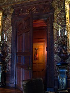 an open door in the middle of a room with ornate wallpaper and wooden floors