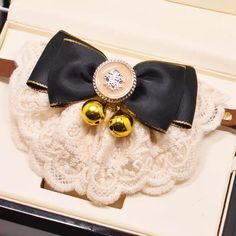 a black and gold bow tie with two bells on top of it in a box