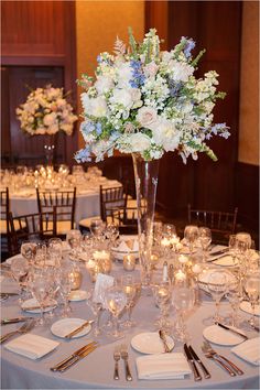 the table is set with white flowers and silverware