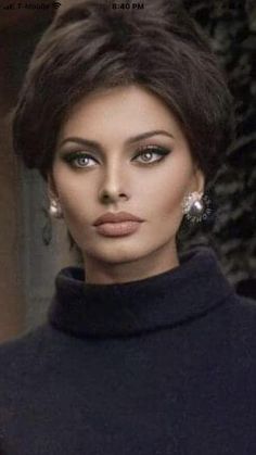 a woman with dark hair and blue eyes posing for a photo in black turtle neck sweater